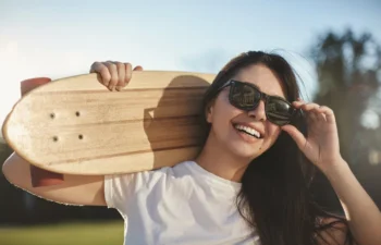 young woman wearing sunglasses and holding a skateboard